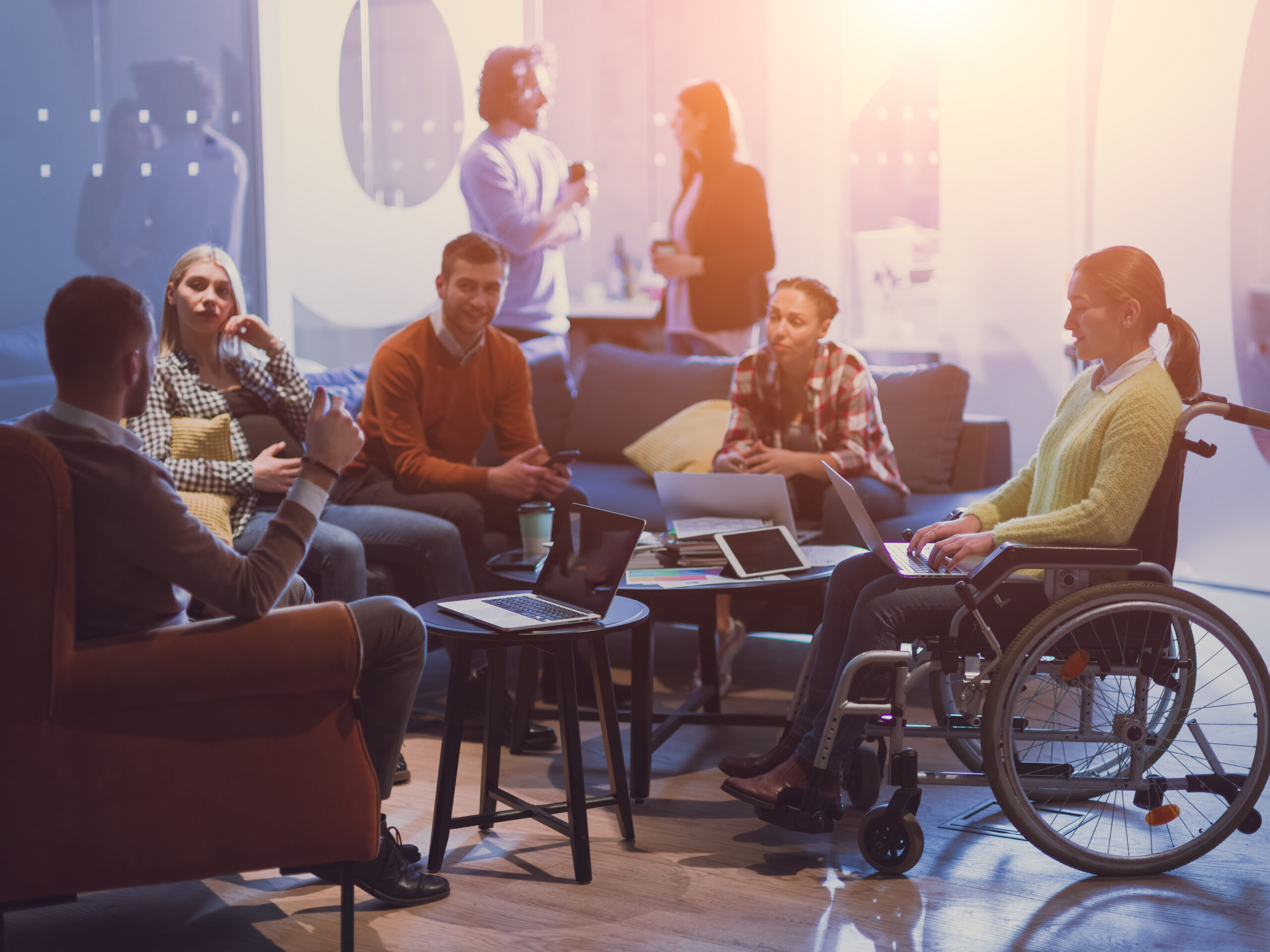 businesswoman in a wheelchair on meeting with her diverse business team brainstorming about ideas and plans in a modern open space coworking office.