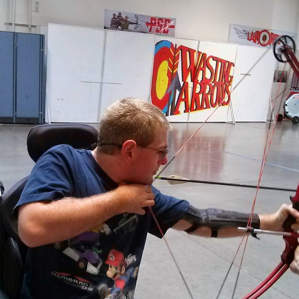 Brenden Hockett draws a bow and arrow while sitting in a wheelchair