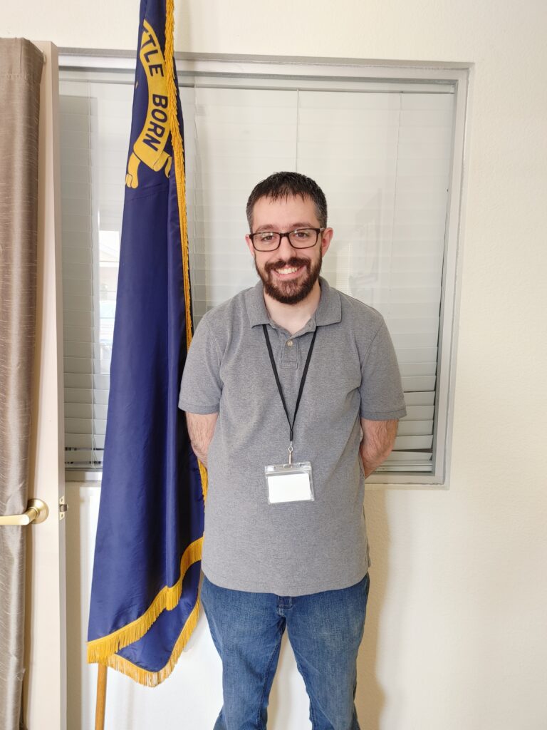 Josh smiles, standing next to a Nevada state flag